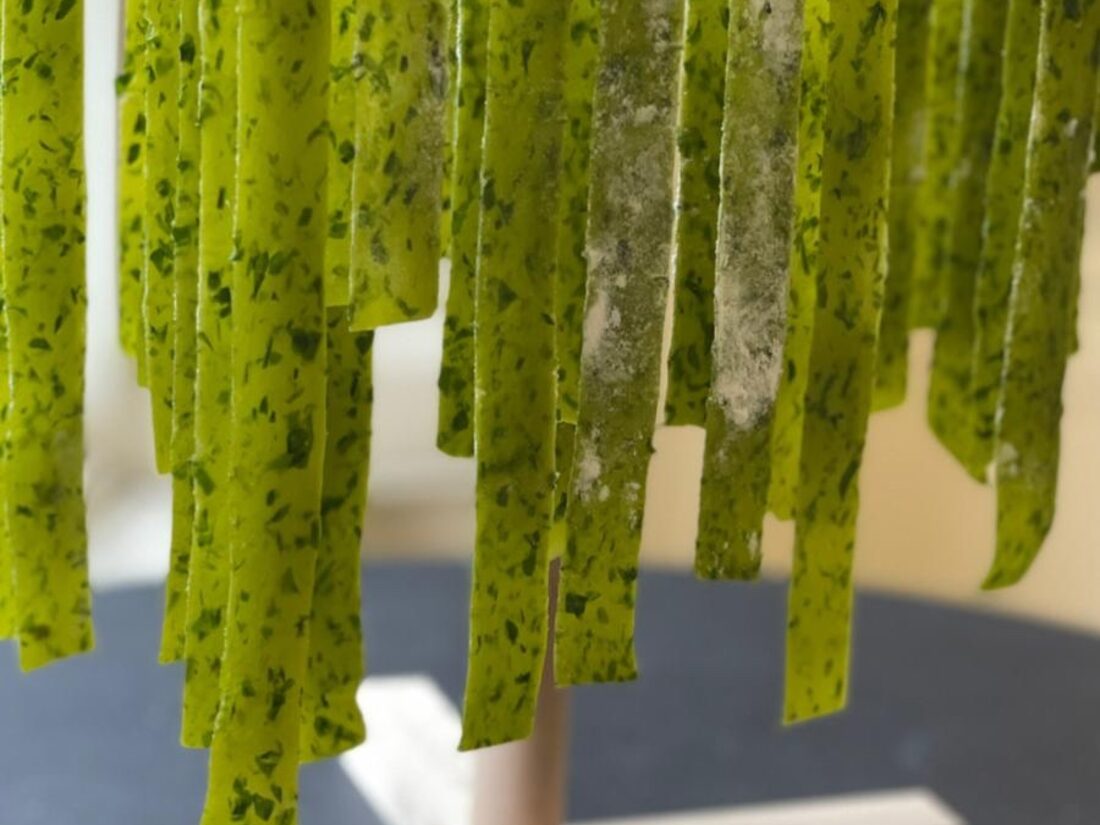 Fresh herb pasta hung to dry on a wooden rack