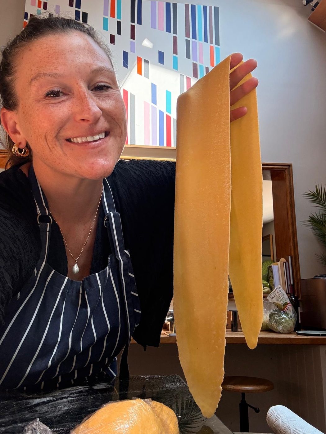 Morgan holding up a fresh, hand-rolled sheet of pasta in the kitchen